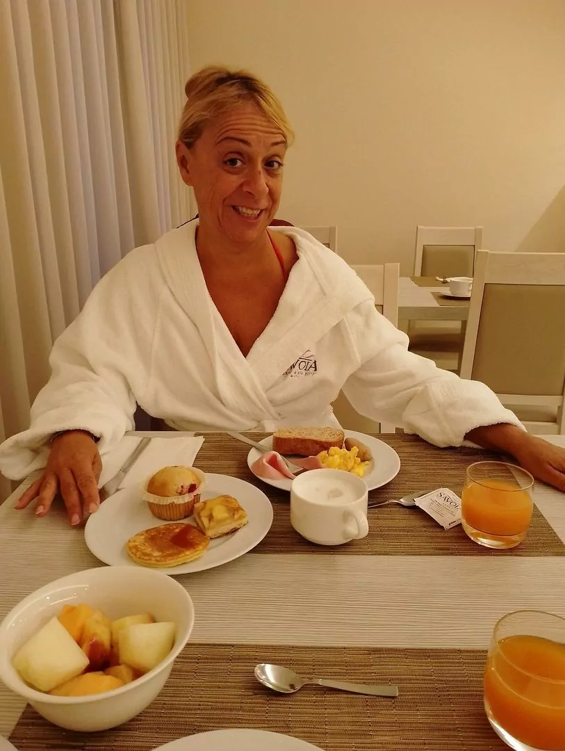 Donna sorridente a colazione in accappatoio.