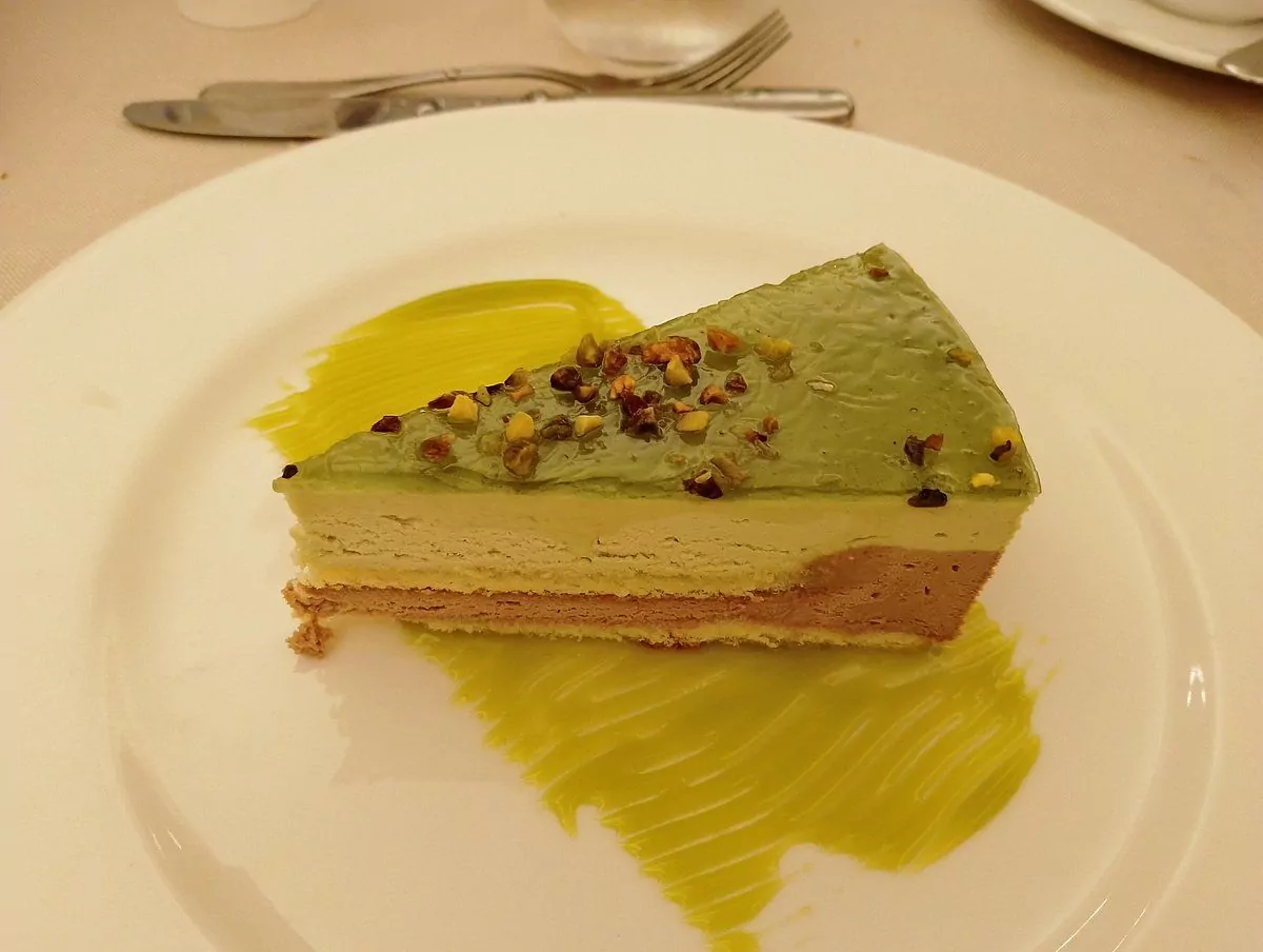 Fetta di torta al pistacchio con glassa e granella.