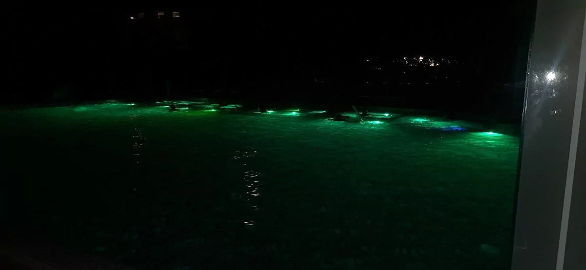 Piscina illuminata di notte con luci verdi.