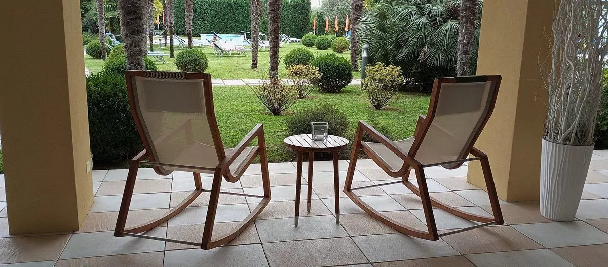 Due sedie a dondolo e tavolino su terrazza esterna.