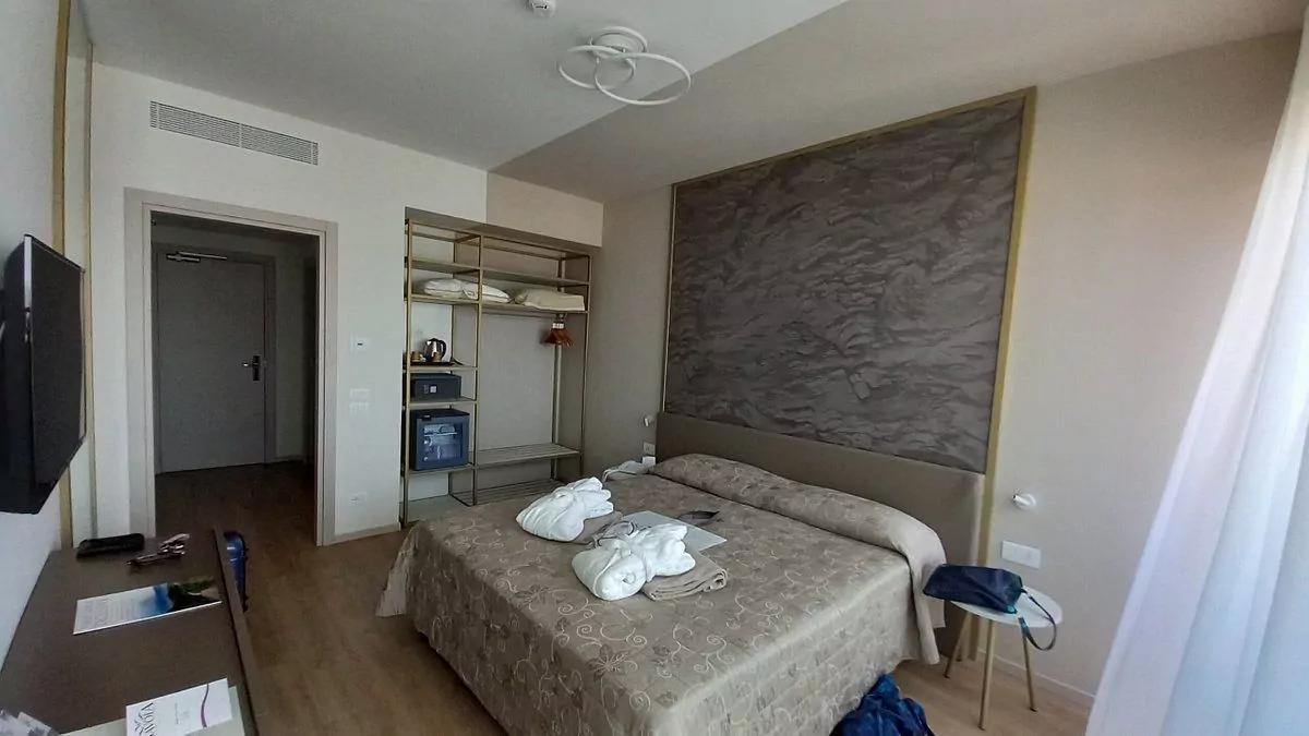 Camera da letto moderna con letto disfatto e TV.