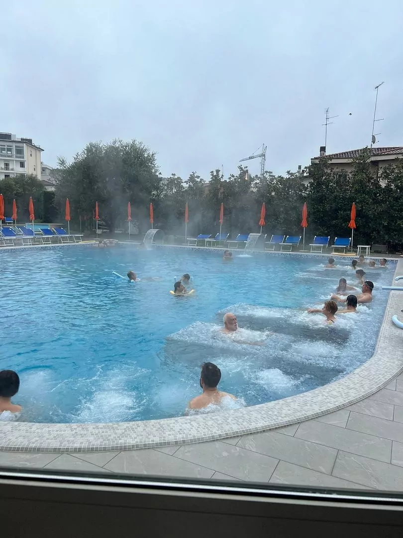 Piscina esterna con persone e vapore.