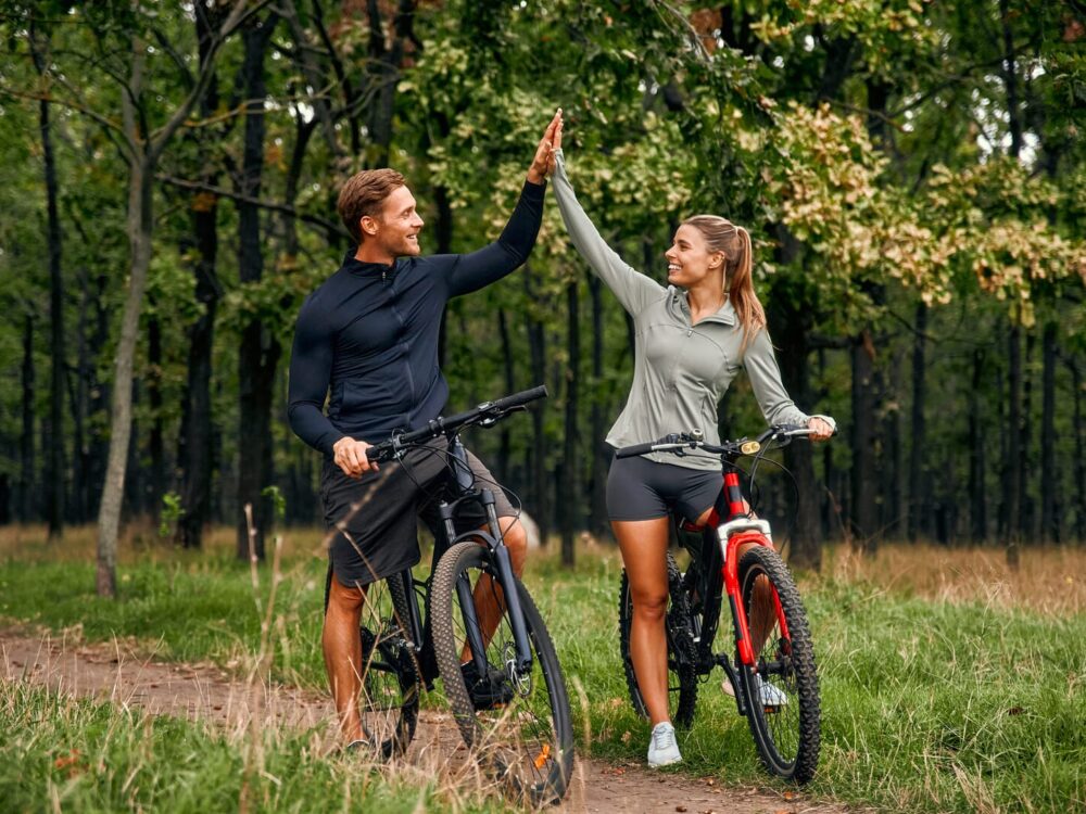 Coppia felice in bici nei boschi