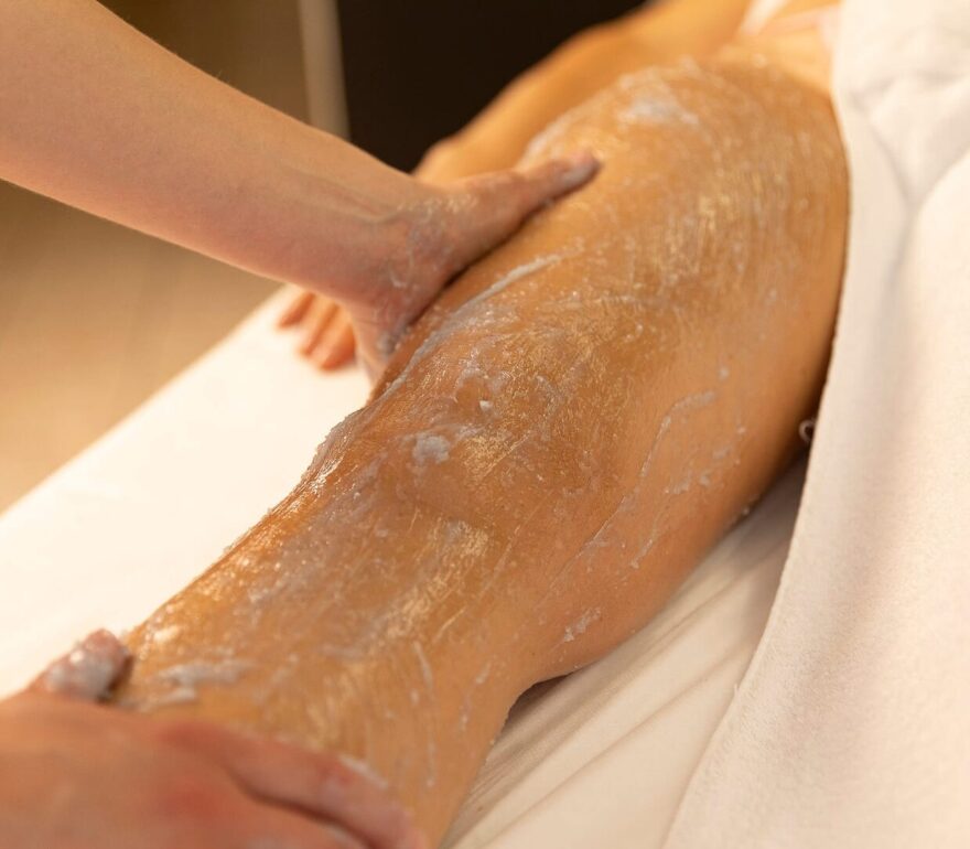 Massaggio alle gambe con crema esfoliante in spa.