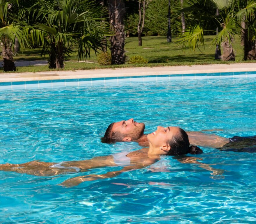 Coppia galleggia in piscina termale soleggiata