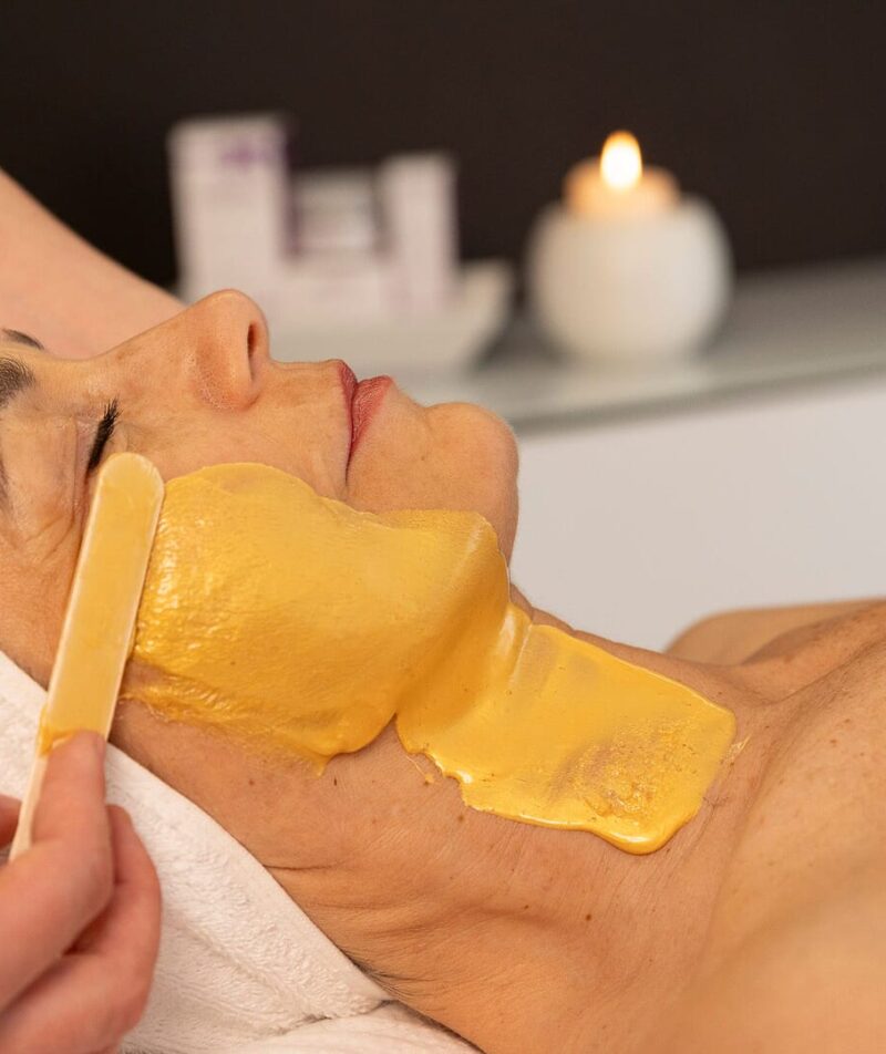 Eine Frau erhält eine Gesichtsbehandlung mit einer goldenen Maske.