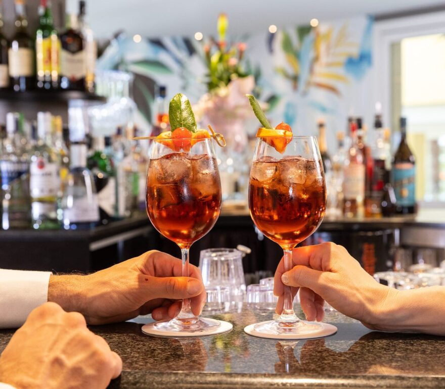 Die Gäste stoßen an der Bar mit Cocktails an