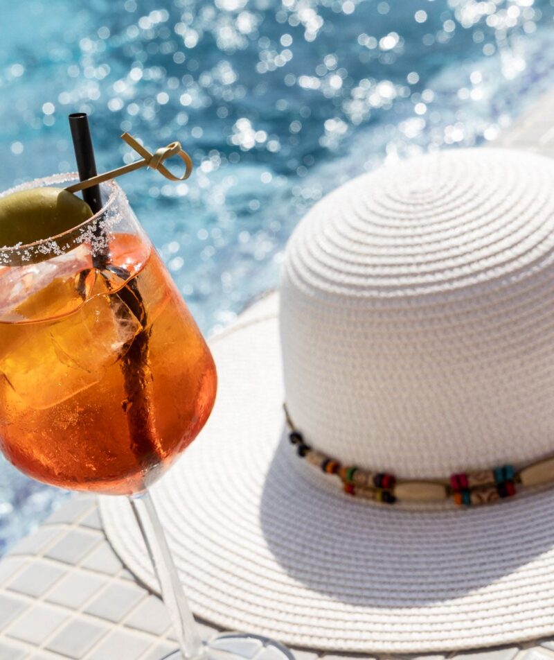 Cocktail e cappello vicino a piscina.